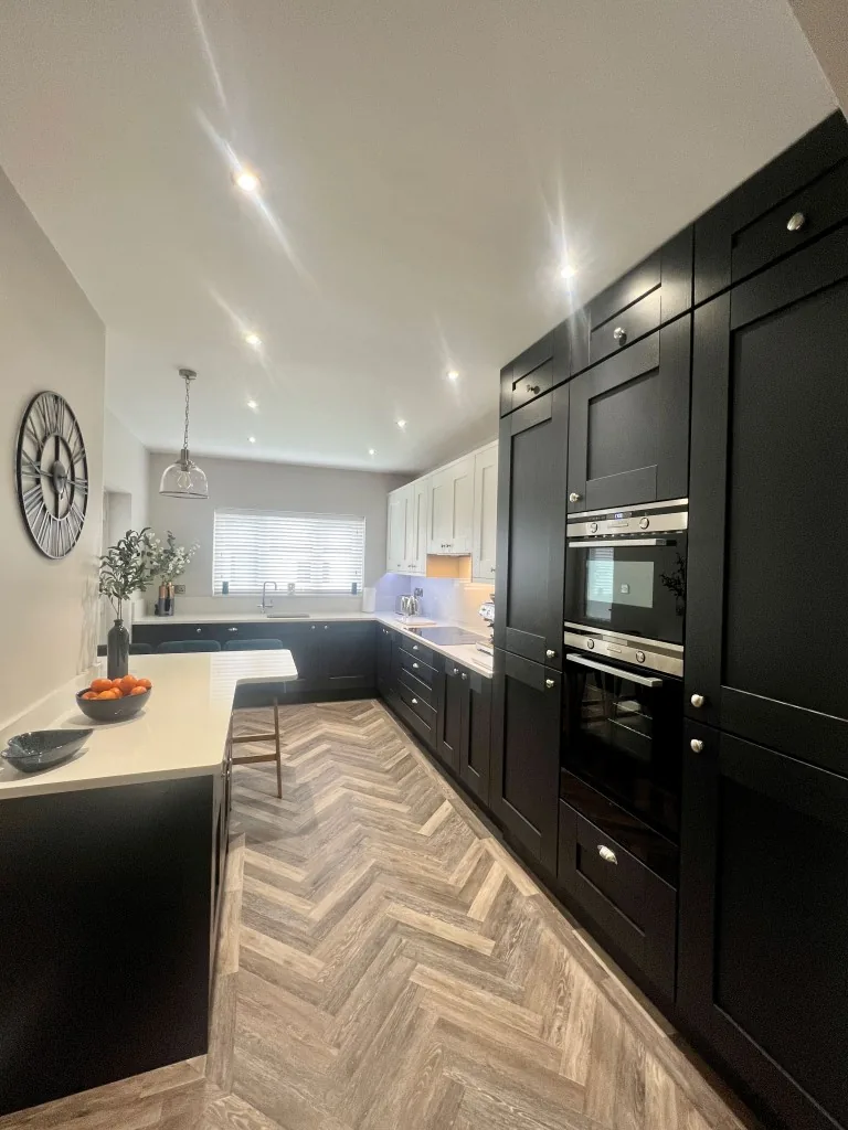 Charcoal painted Shaker kitchen with tall units, built-in ovens and herringbone flooring